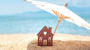 Small cutout of home on beach under umbrella.