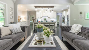 Long view of hardwood floor living room with gray couches looking into kitchen.